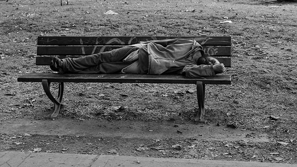 homeless man sleeping on a bench