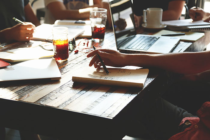 group of people with laptops and notebooks working at a table